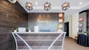 Een receptiebalie met een houten afwerking, een bordje met de tekst 'Beverly Inn' en drie geometrische hanglampen.