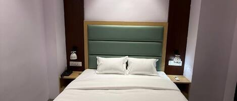 A hotel room with a large bed, two bedside tables, and a wooden headboard.