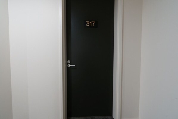 Une porte noire fermée, avec une plaque indiquant le numéro de la chambre : 317.
