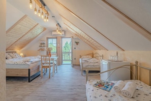 Ein gemütliches Schlafzimmer im Dachgeschoss mit zwei Betten, einem kleinen Tisch und einem Stuhl.