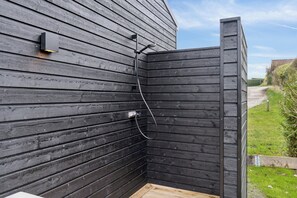 Un mur extérieur en bois intégrant une cabine de douche.