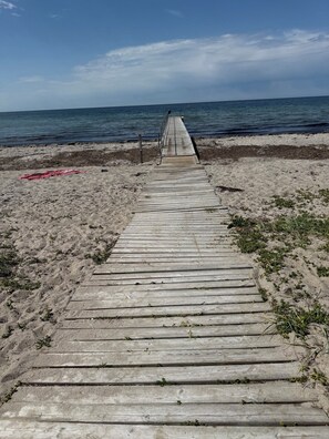 A wooden boardwalk leading to the beach with a clear view of the ocean. - Charming newly built cottage 300 m from beach (Karrebæksminde)
