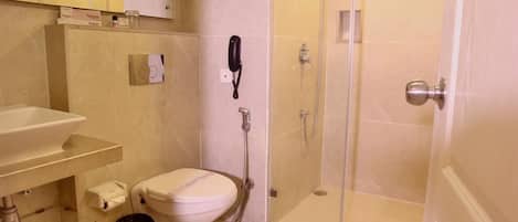 A bathroom with a toilet, a sink, a shower, and a telephone.