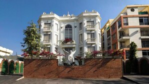 A multi-story building with a white facade, balconies, and a brick base. - Hotel Magenta - A unit of Fortune Global (Jaipur)