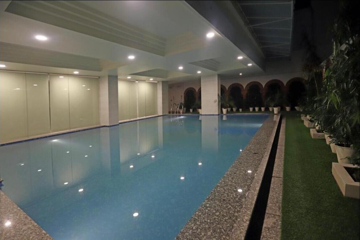 Una piscina interior con vista despejada de toda su longitud, rodeada de paredes de diseño moderno y plantas en macetas.