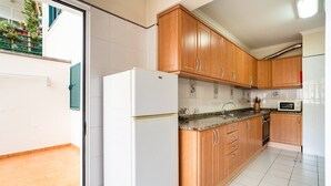 Eine Küche mit Holzschränken, einem weißen Kühlschrank, einer Arbeitsplatte aus Granit und einer Mikrowelle.