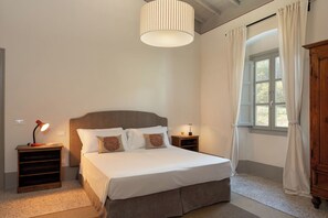 Una camera da letto con un letto grande, due comodini, una lampada, una finestra con tende e un armadio in legno.