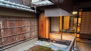 Perinteinen japanilaistyylinen sisäpiha, jossa on puinen aita, kivipolku ja pieni puutarha-alue.