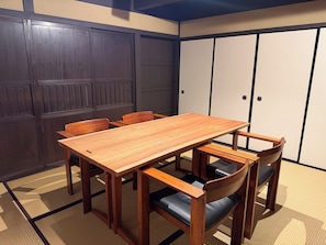 A traditional Japanese-style room with tatami mat flooring, a wooden table, and chairs. - NAGAEKE RESIDENCE (Kyoto)