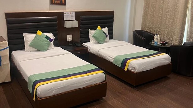 Une chambre d’hôtel avec deux lits, un ventilateur de plafond, une table de chevet avec une lampe et une fenêtre avec des rideaux.