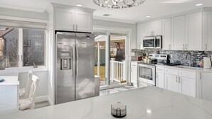 A modern kitchen with white cabinetry, stainless steel appliances, and a large island.