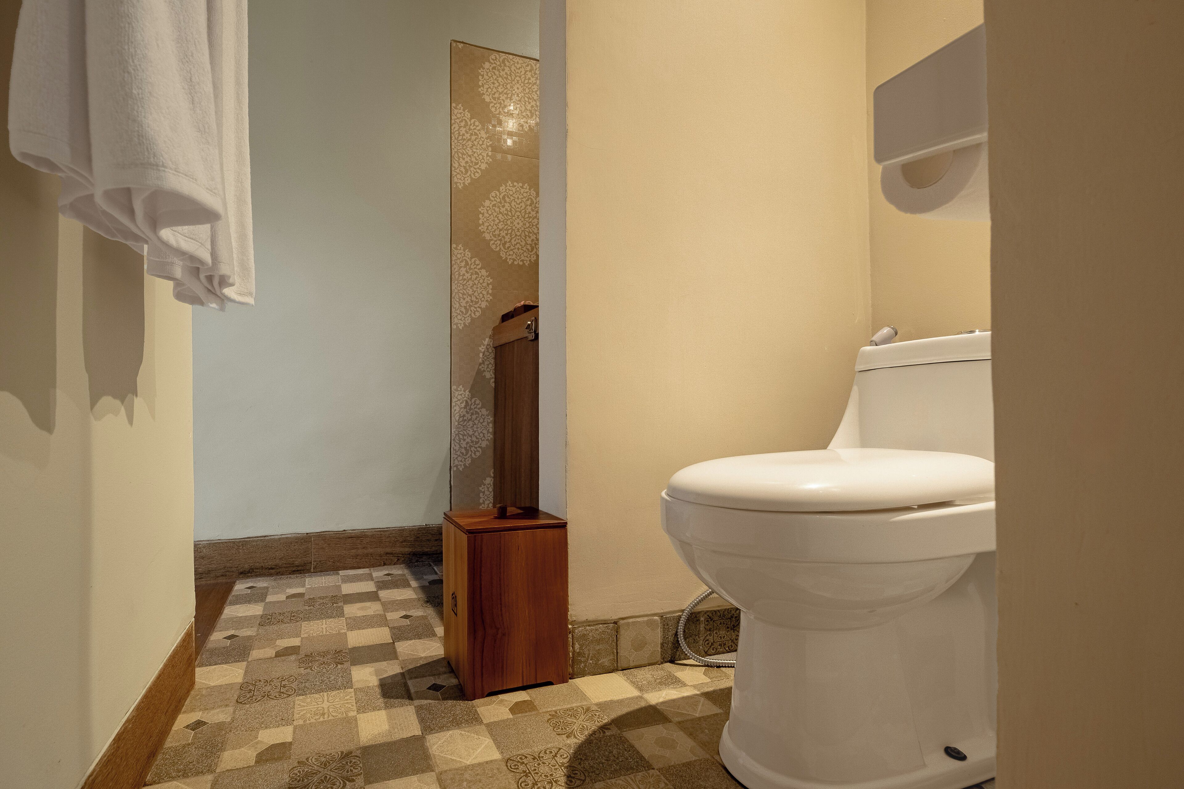 A bathroom with a checkered floor, a white toilet, and a wooden cabinet.