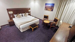 Una camera d'albergo con un letto grande, un tavolino rotondo, due sedie, un comodino e un quadro appeso al muro.
