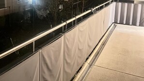 A balcony with a metal railing, a concrete floor, and a view of residential buildings in the background. - Cozy high-quality furnished apartment (Wiesbaden)