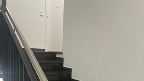 A staircase with black steps and a metal handrail, leading to a white door. - Cozy high-quality furnished apartment (Wiesbaden)