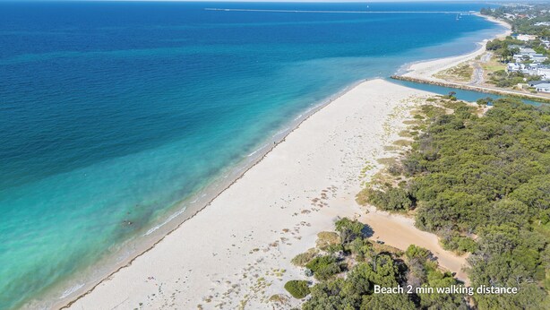 Una playa con agua turquesa cristalina, una orilla de arena y un sendero que lleva a un muelle.