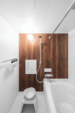 A modern bathroom with a wooden accent wall, a white toilet, a bidet, and a bathtub. - NOBLE301 (Sapporo)