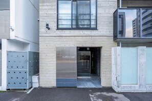 A modern building with a wooden facade, large windows, and a metal entrance door labeled "ALPHA NINE". - NOBLE301 (Sapporo)