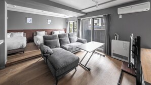 Een moderne hotelkamer met een bank, een bed, een televisie en een groot raam met gordijnen.
