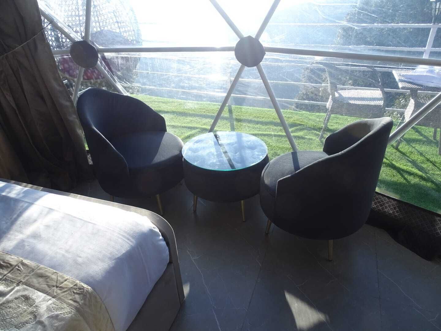 Una habitación moderna con una cama, dos sillones y una mesita.