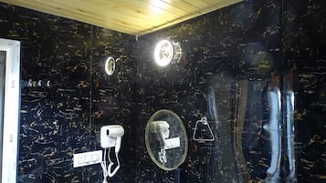 Un baño con pared de mármol negro, un secador de manos blanco, un espejo y un perchero para toallas.