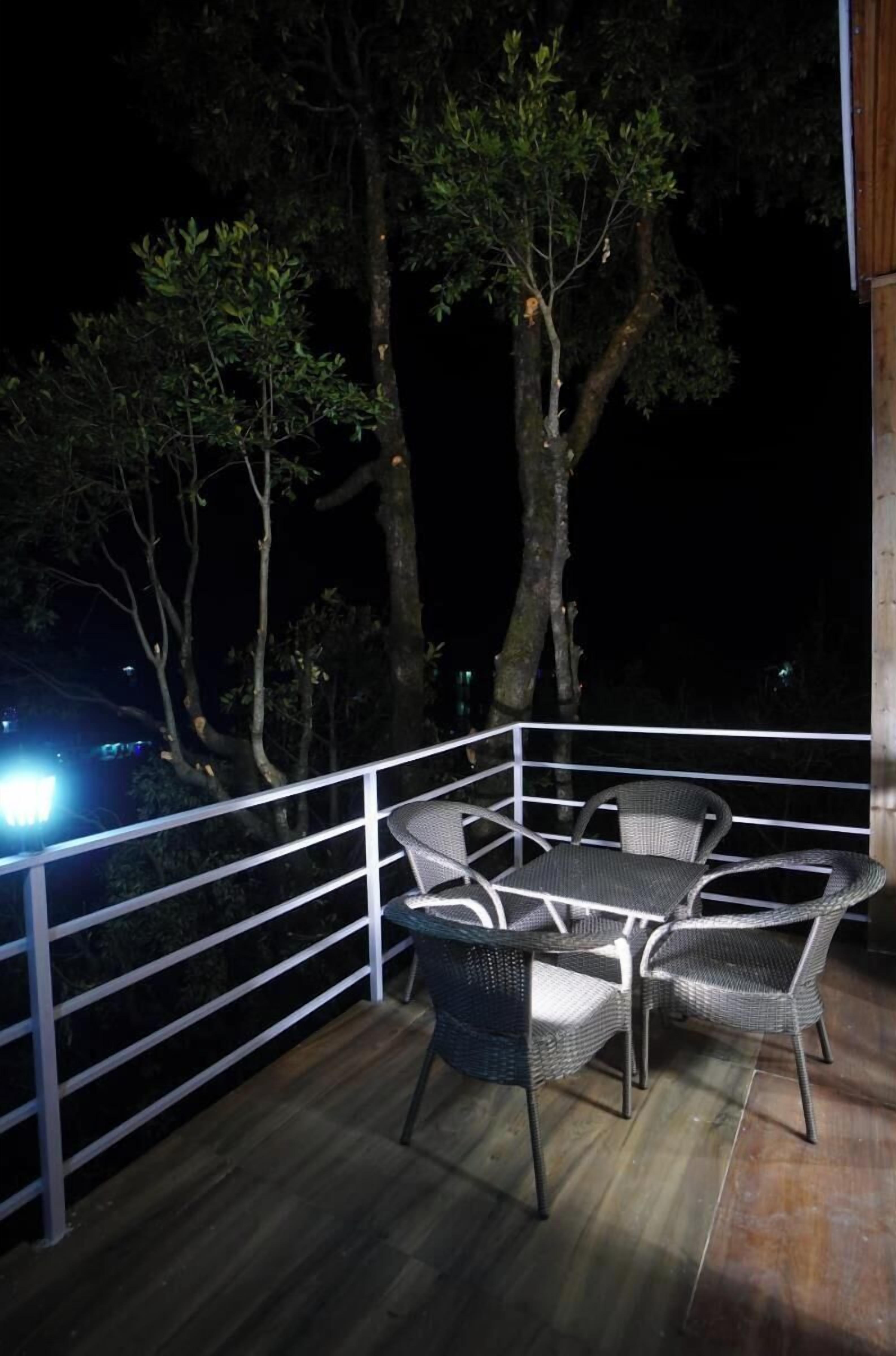 Un terrazzo in legno con mobili in vimini e una ringhiera bianca.