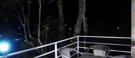 Un terrazzo in legno con mobili in vimini e una ringhiera bianca.