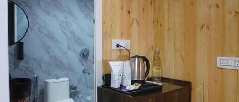 A bathroom with wooden walls, a marble-tiled shower area, a white toilet, and a dark wooden vanity with towels.