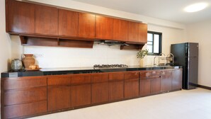 A modern kitchen with wooden cabinets, a black countertop, a gas stove, and a black refrigerator. - Amazing 3-bedroom house in charming Mae Rim, Chiangmai (Tambon Rim Tai)