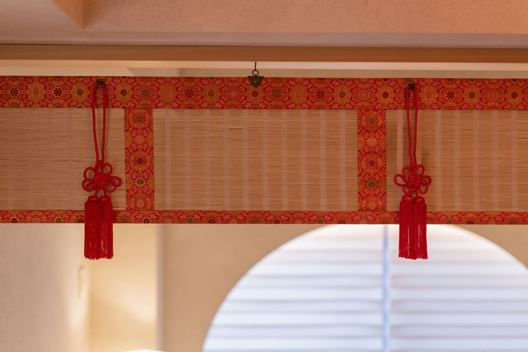 Une pièce dotée d’un paravent japonais traditionnel en papier de riz (shoji) et d’une frange décorative rouge suspendue au plafond.