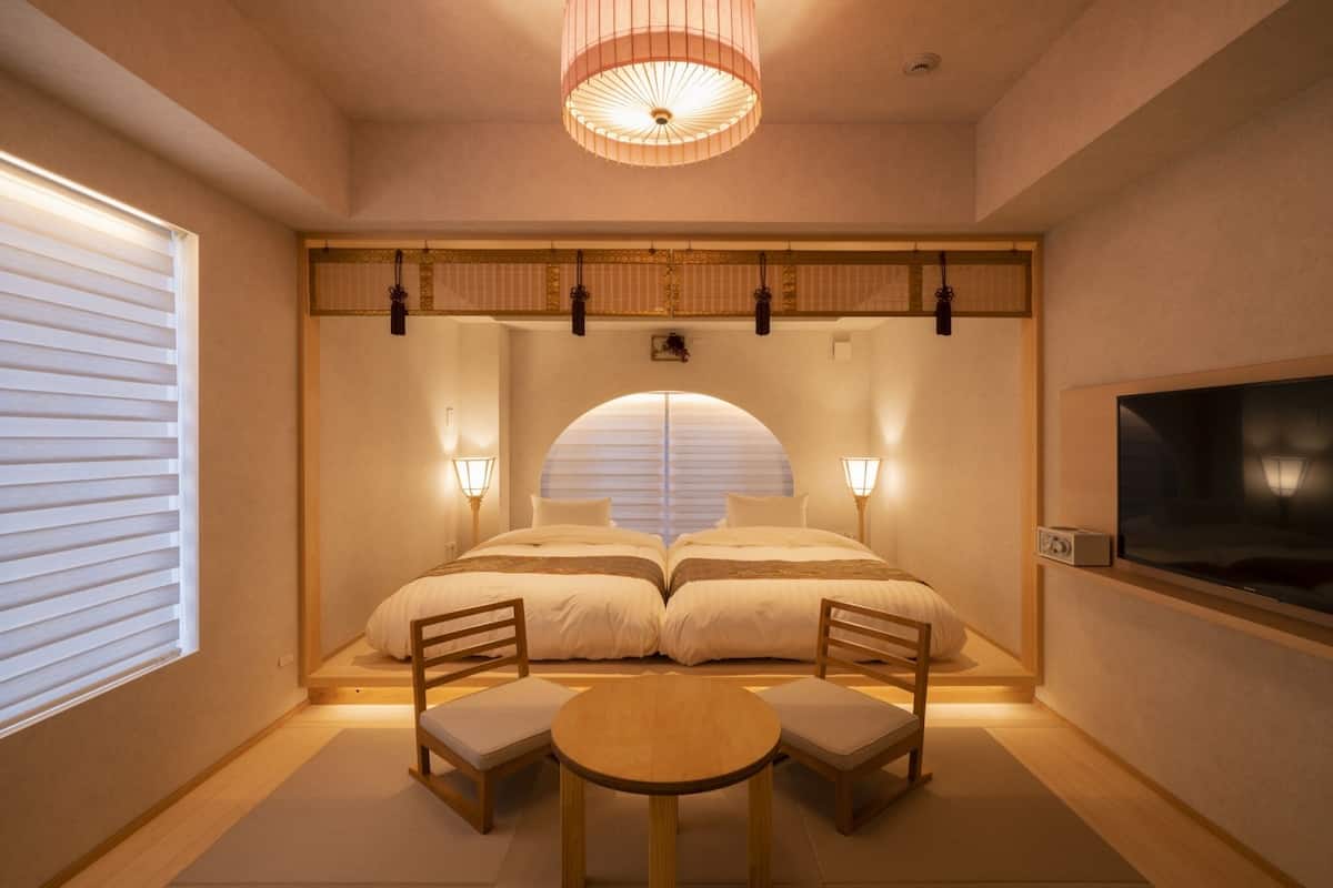 A room with two beds, a TV, and a table with chairs.
