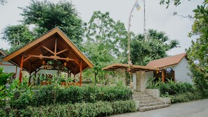 A rustic wooden structure with a tiled roof, surrounded by lush greenery and a stone staircase leading to a door. - Nuansa Penida Cottage (Penida Island)