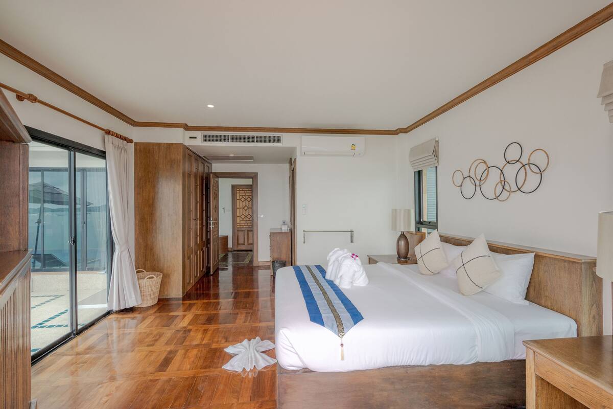 Une chambre d’hôtel avec un grand lit, un plancher en bois, une porte-fenêtre coulissante et une vue sur l’extérieur.