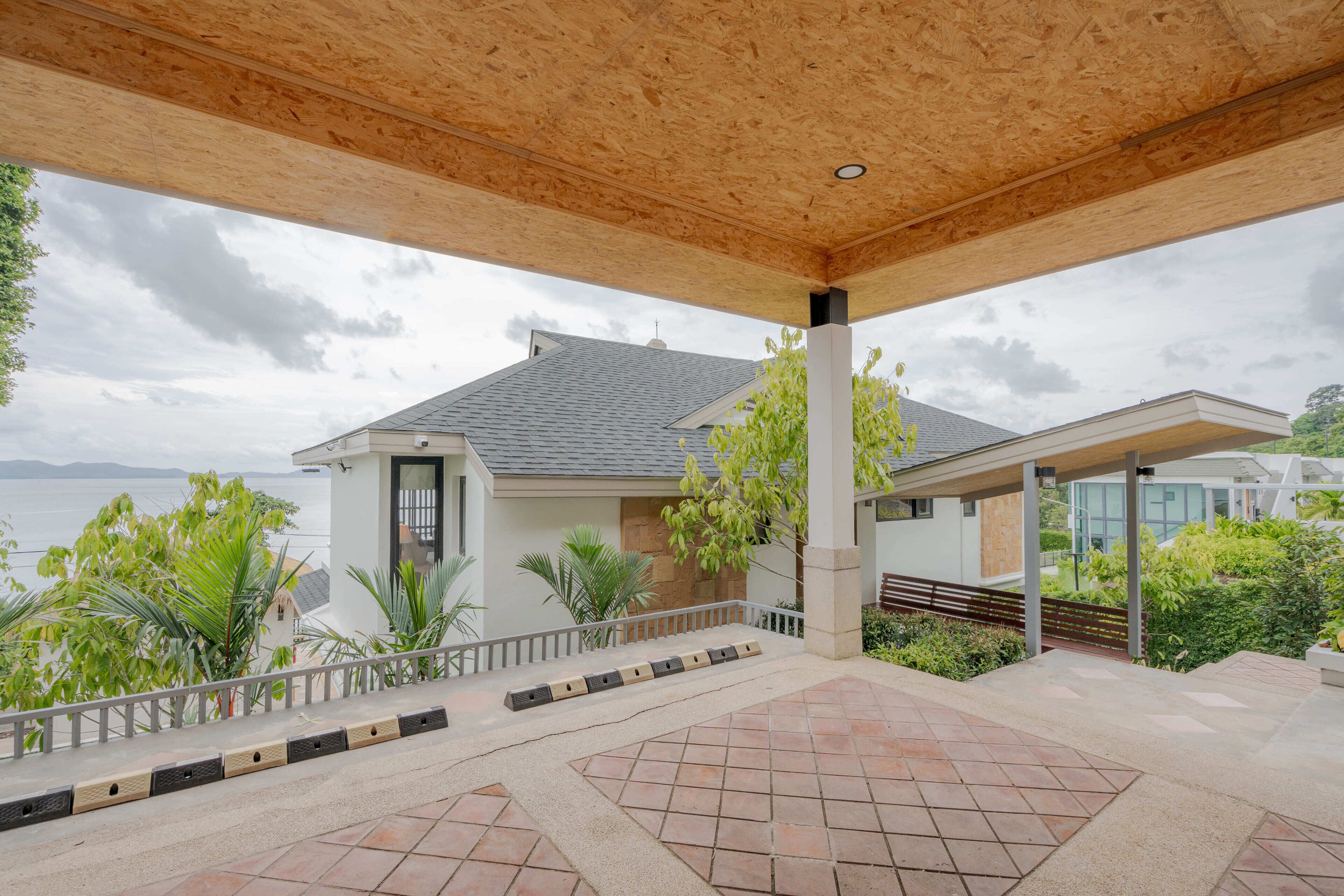 A covered outdoor area with a view of a house and the sea.