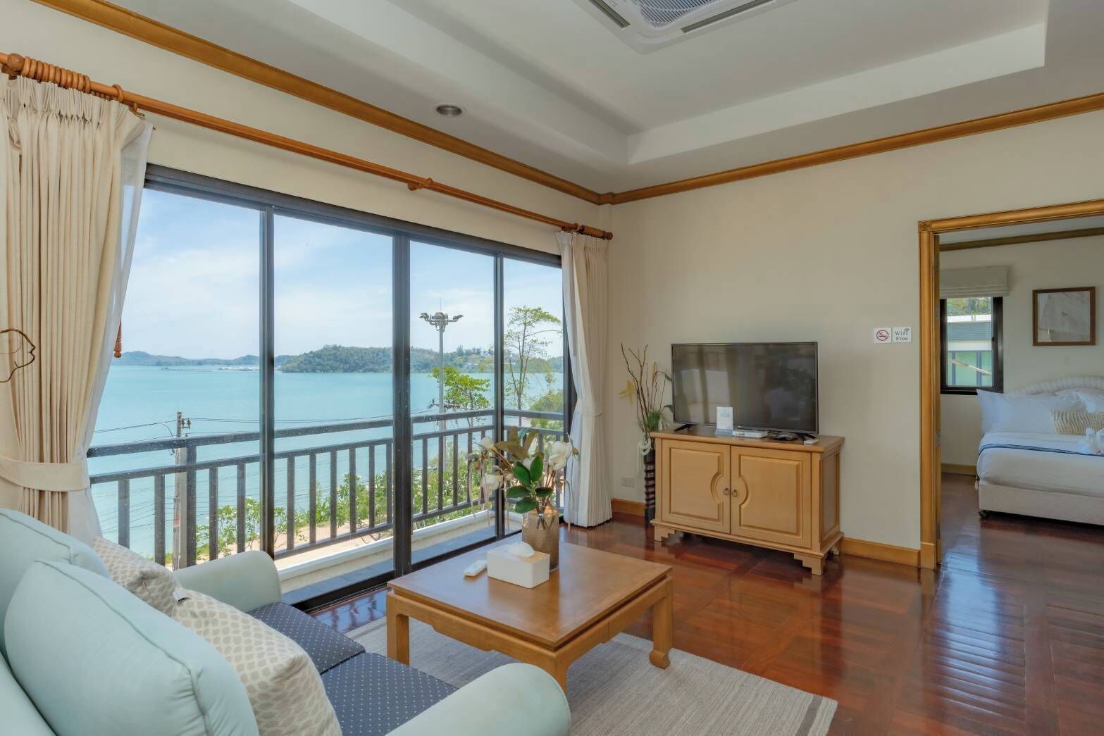 A room with a large window, a television, a sofa, a coffee table, and a cabinet.