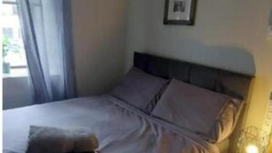 Ein Schlafzimmer mit einem Bett, einer Nachttischlampe und einem gerahmten Bild an der Wand.