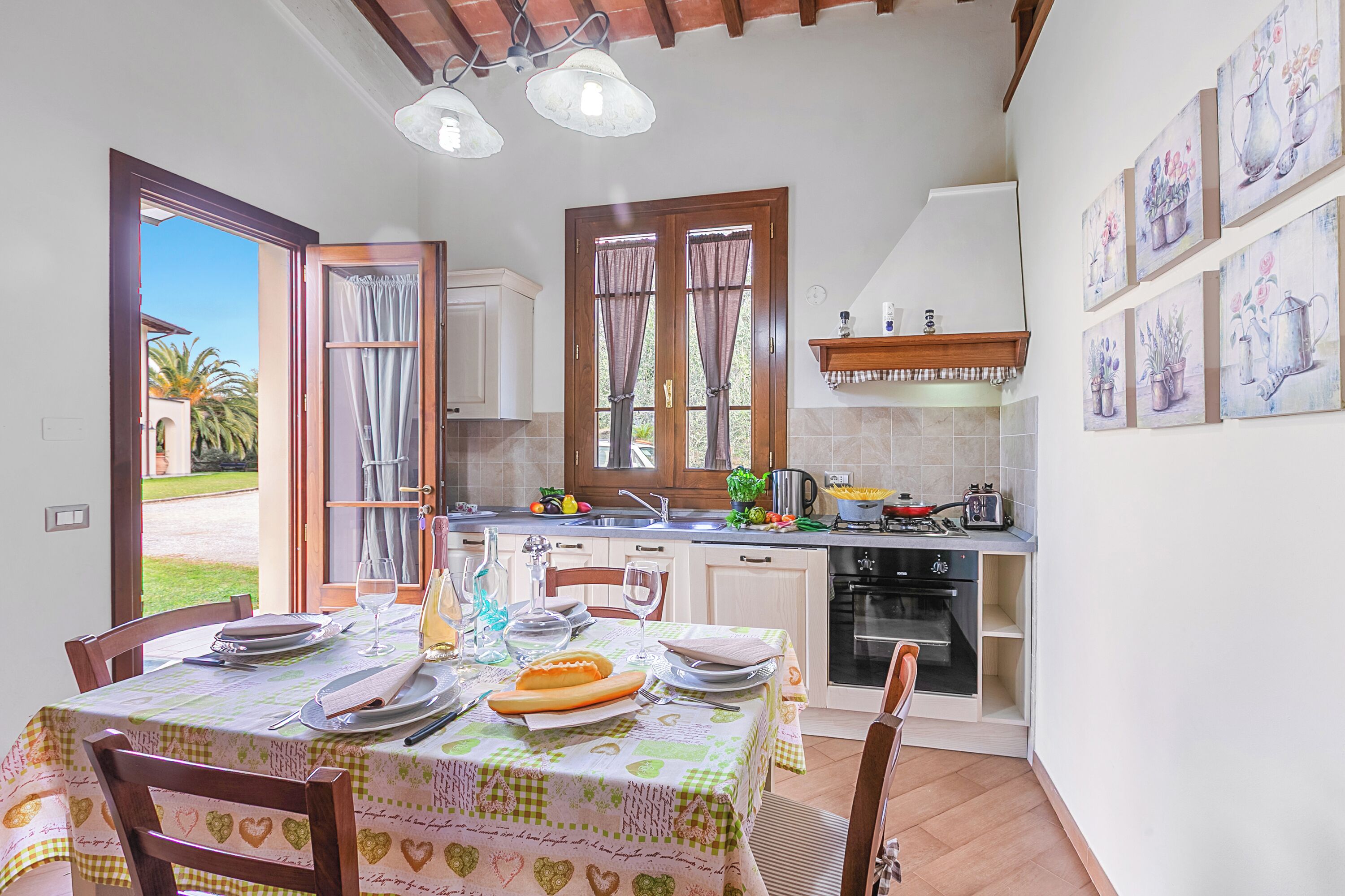 Un coin repas avec une table dressée pour quatre personnes, une cuisine équipée d’appareils modernes et une vue sur l’extérieur.
