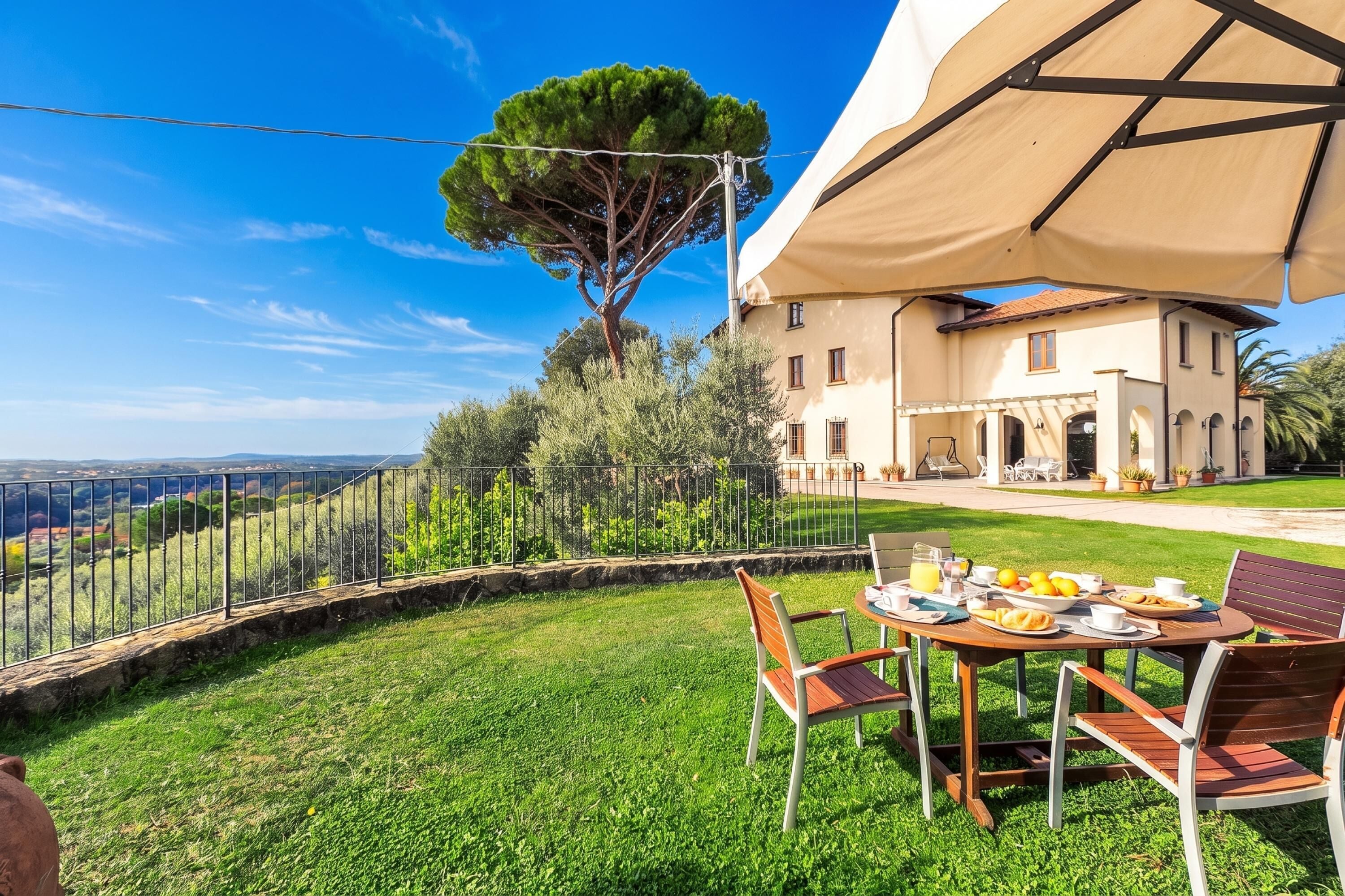 A dining area with a table set for two, overlooking a lush green landscape and a large tree.