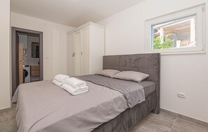 A bedroom with a bed, a wardrobe, a window, and a washing machine in the adjacent room.
