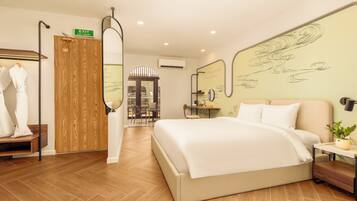 Ein Hotelzimmer mit Bett, Kleiderschrank, Spiegel, Schreibtisch mit Pflanze und Blick auf die Stadt durch das Fenster.