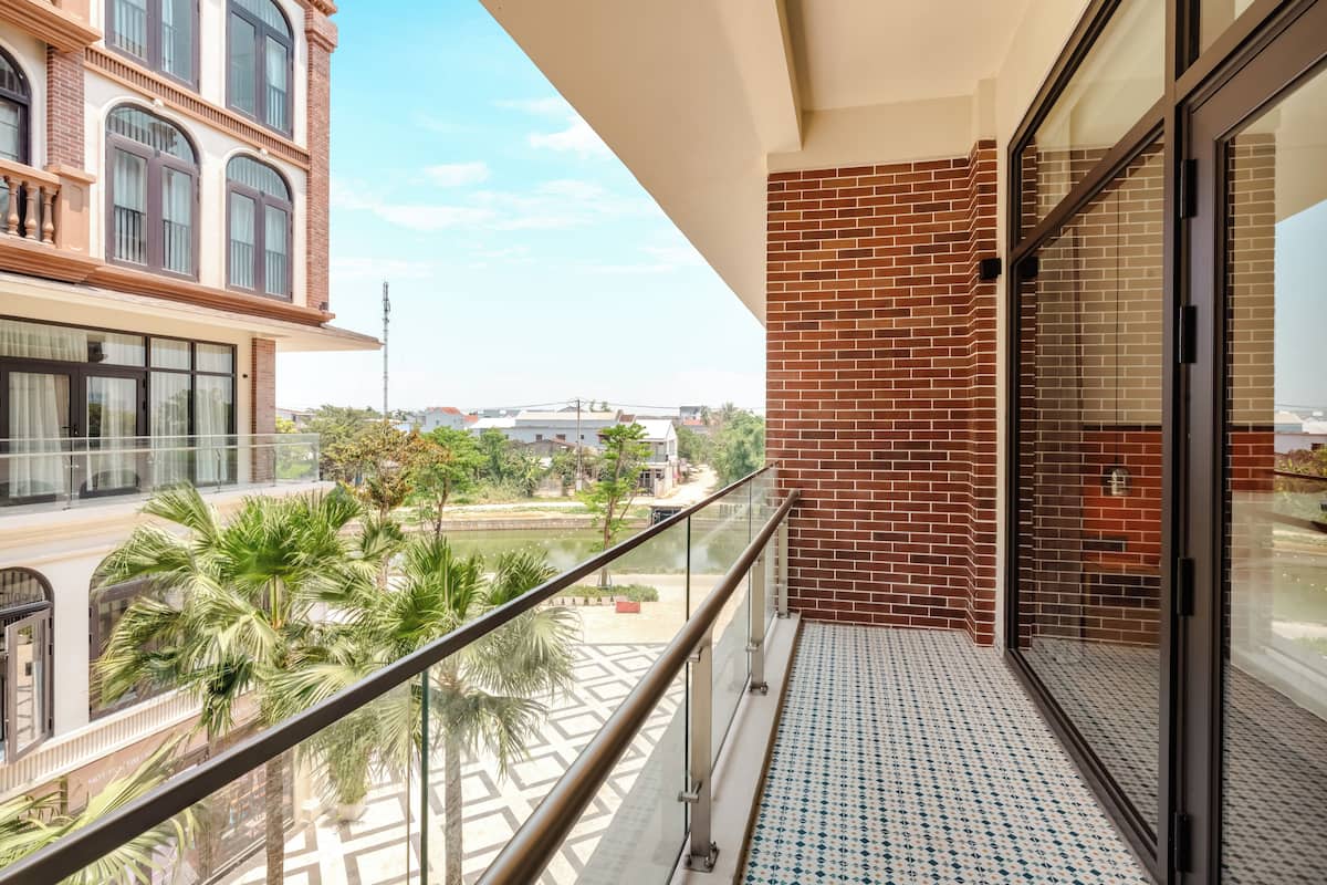 Un balcone con pavimento decorato, una porta in vetro e vista su un edificio in mattoni e palme.