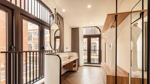 A modern bathroom with a large mirror, a sink, and a shower area. - Lumiere Boutique Vy Da (Hue)