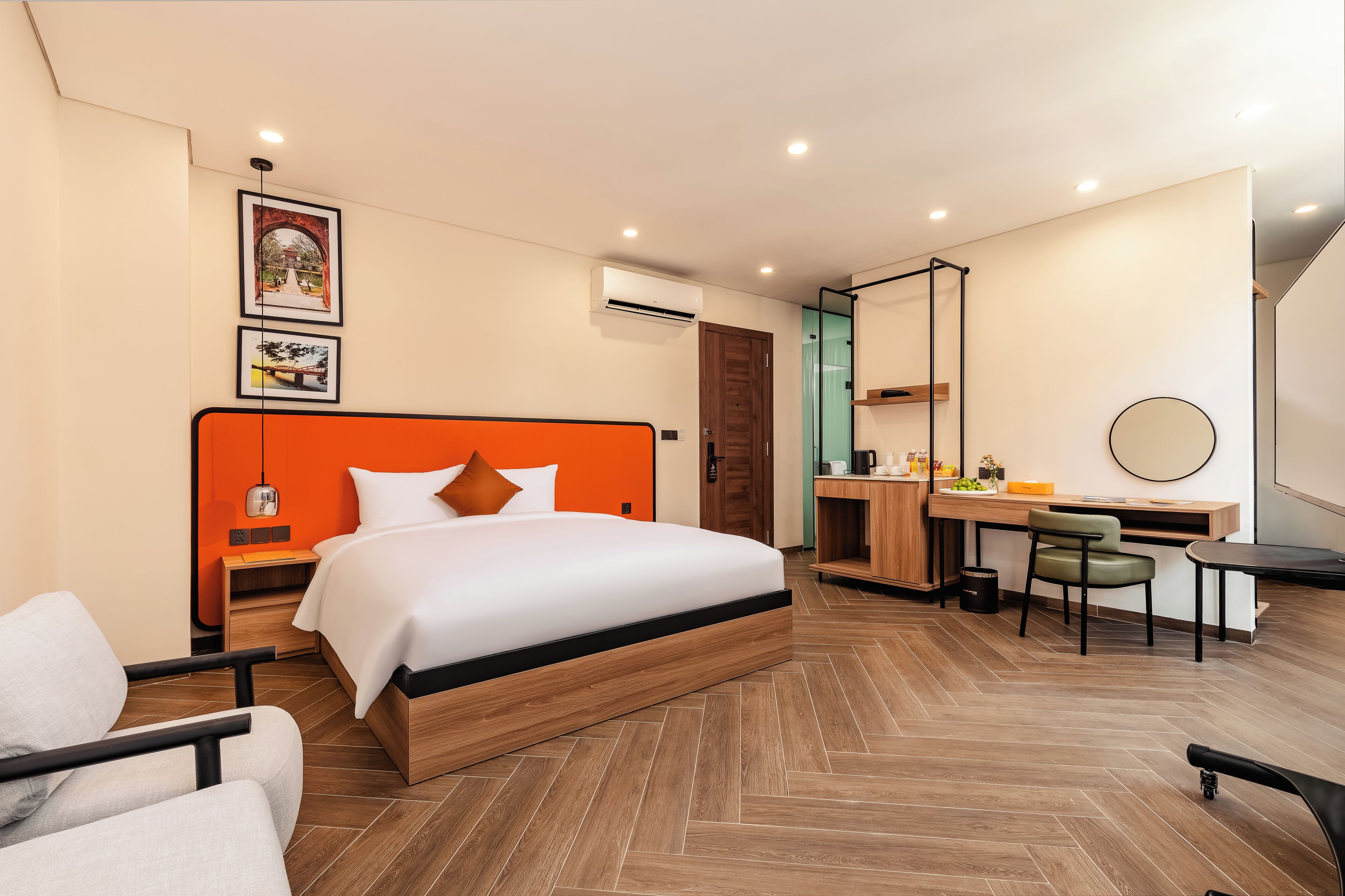 A modern hotel room with a bed, desk, chair, and a small table.