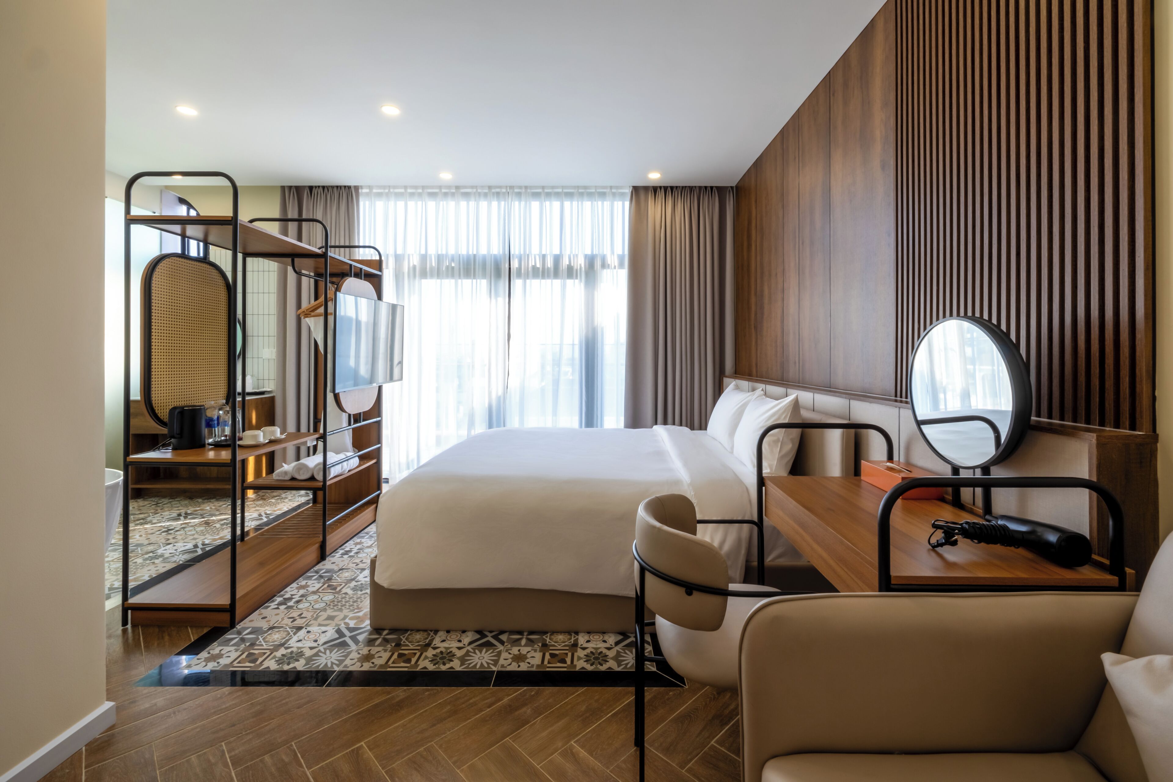 Une chambre d’hôtel moderne avec un grand lit, un bureau avec une chaise, un miroir et une armoire.