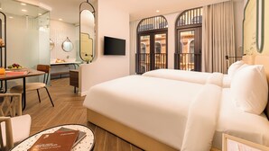 A hotel room with a bed, a desk, a chair, a TV, and a large window with curtains. - Lumiere Boutique Vy Da (Hue)