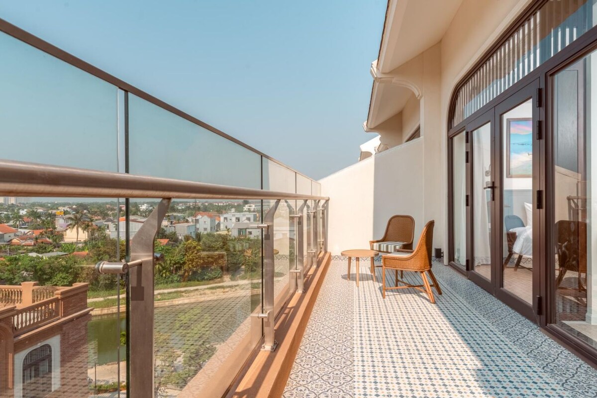 Een balkon met glazen hekwerk, rieten stoelen en een vloer met een patroon.