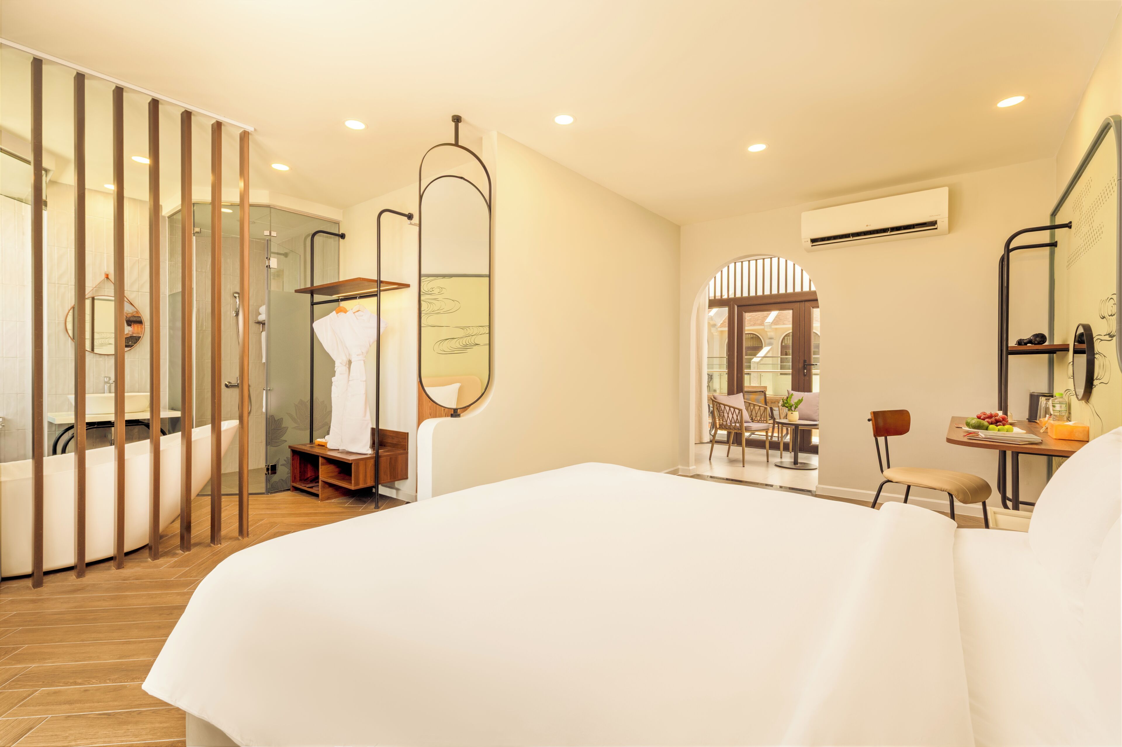 A hotel room with a large bed, a bathroom with a bathtub, a shower, and a seating area with a table and chairs.