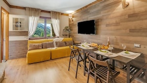 Una sala de estar moderna con piso de madera, un sofá amarillo, una mesa de comedor puesta con platos, vasos y una botella.