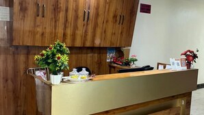 A reception desk with wooden cabinets above and a marble-tiled floor. - JSB PALACE (Varanasi)