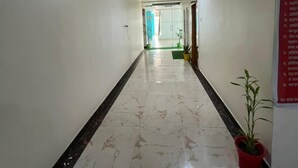 A hallway with white walls, a marble floor, and a red sign on the right. - JSB PALACE (Varanasi)